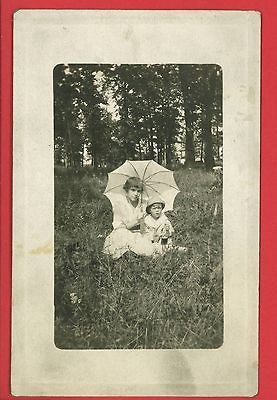 RPPC GIRL & BABY BOY WITH POP SODA BOTTLE SITTING IN GRASS W/ PARASOL